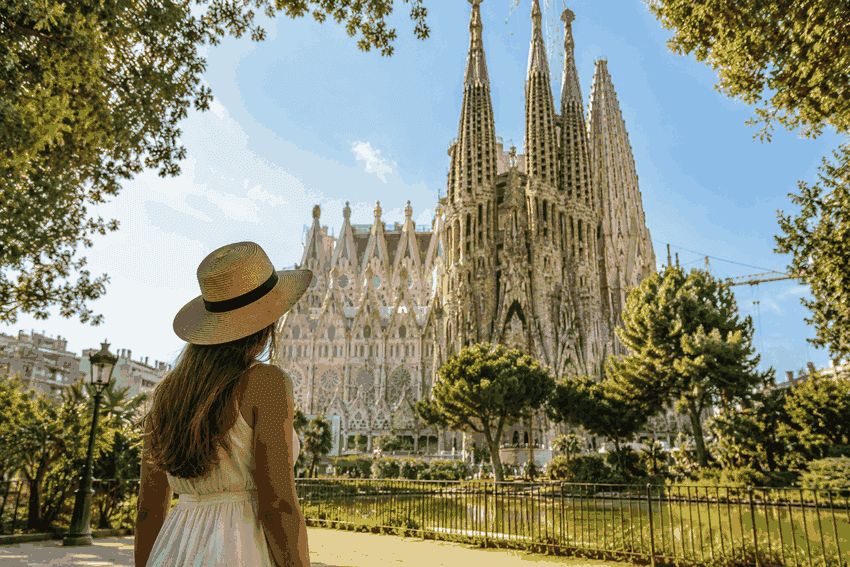 Visitor in appropriate summer clothing looking at Sagrada Família in Barcelona from the park.